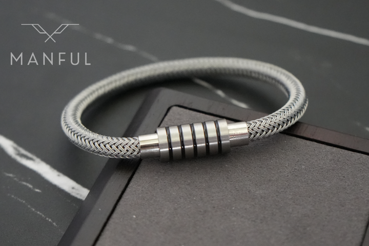 Steel Wire Bracelet Silver, resting on a dark marble surface with white veining