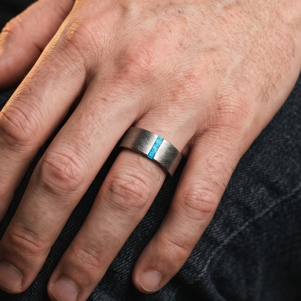 Mens Gemstone Jewellery Collection, a brushed silver tungsten band with a blue opal inlay worn on a man's hand