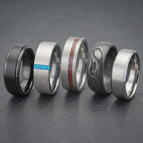 Mens Rings Collection, five bands in black, brushed silver, Damascus pattern and blue or red inlay on dark slate