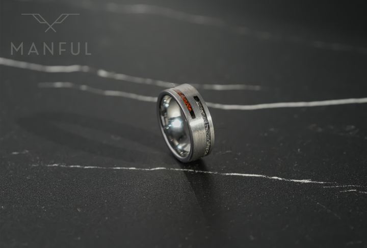 Meteorite & Dinosaur Bone Inlay Band, tilted on a dark marble surface showing the mixed inlay stripe