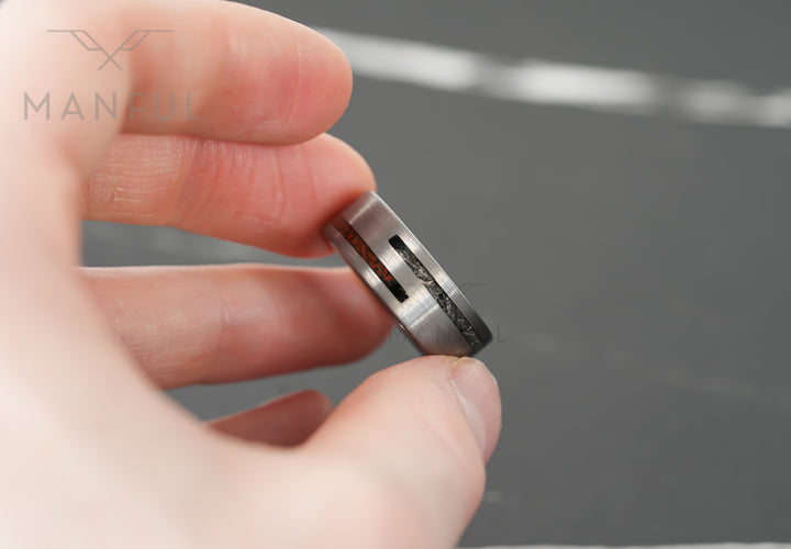 Meteorite & Dinosaur Bone Inlay Band, held between finger and thumb in a close-up of the inlay edge