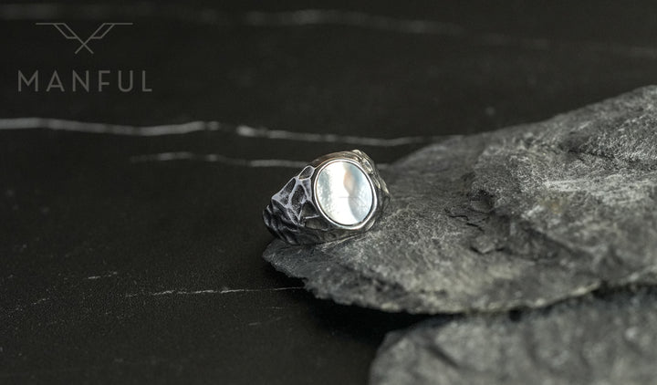 Mother of Pearl Signet Ring, resting against grey slate rocks on dark marble