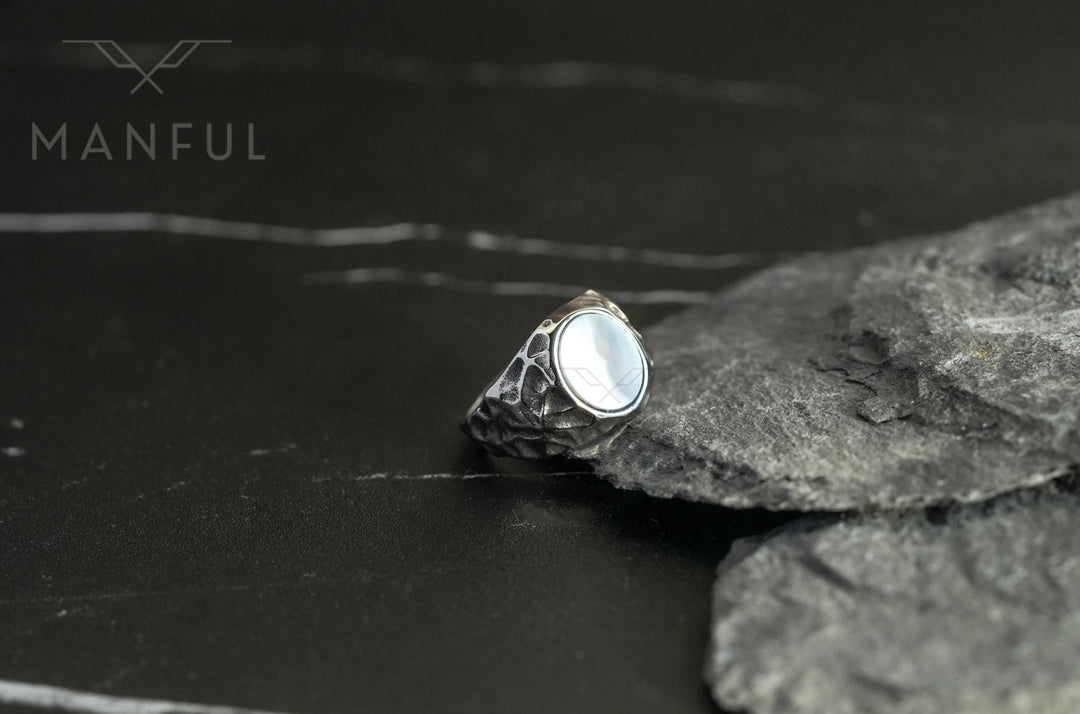 Mother of Pearl Signet Ring, resting against grey slate rocks from a wider angle