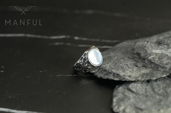 Mother of Pearl Signet Ring, resting against grey slate rocks from a wider angle