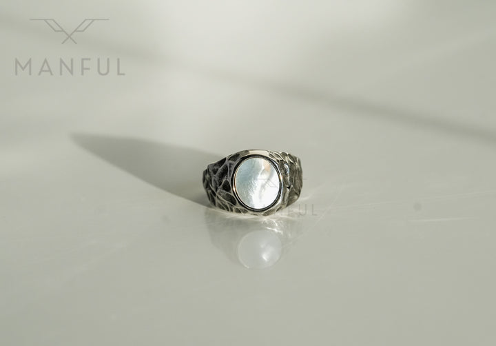 Mother of Pearl Signet Ring, standing upright on a plain white surface with a soft reflection