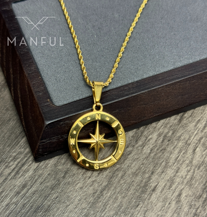 North Star Compass Pendant Necklace Gold, propped against a stone block on wood