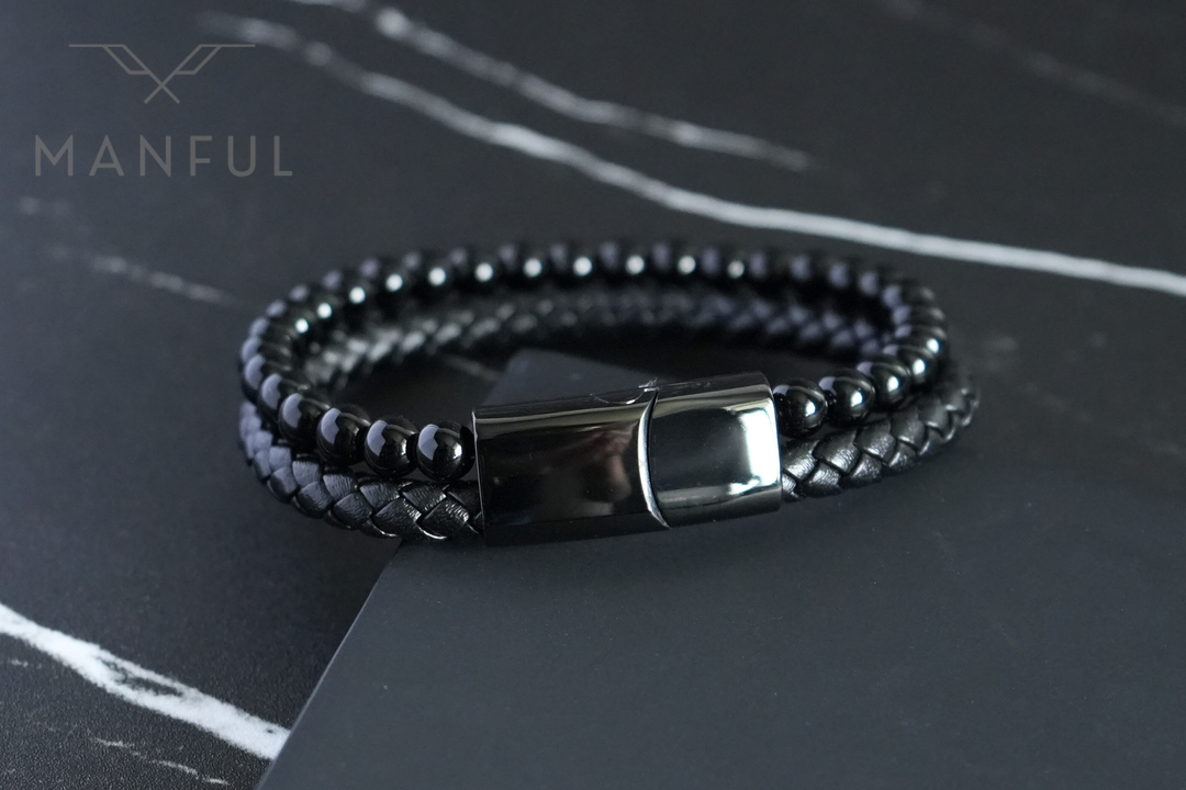 Onyx Bead And Leather Bracelet, coiled on a dark marble surface with the clasp facing the camera