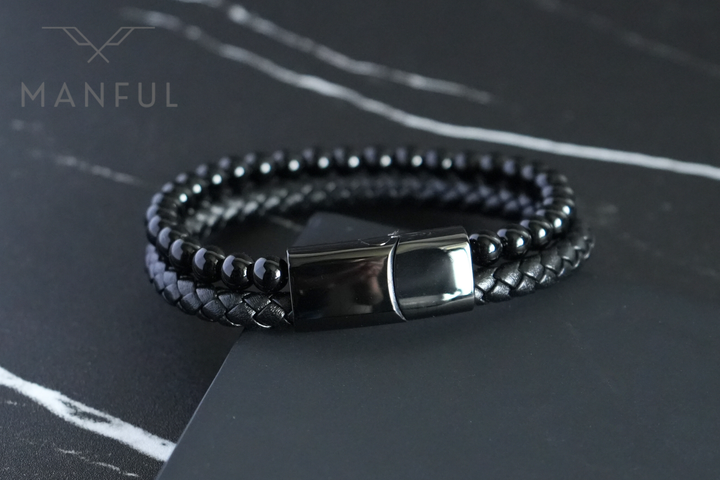 Onyx Bead And Leather Bracelet, coiled on a dark marble surface with the clasp facing the camera