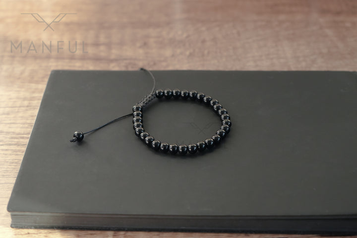 Onyx Bead Bracelet, laid flat on top of a dark notebook on wood