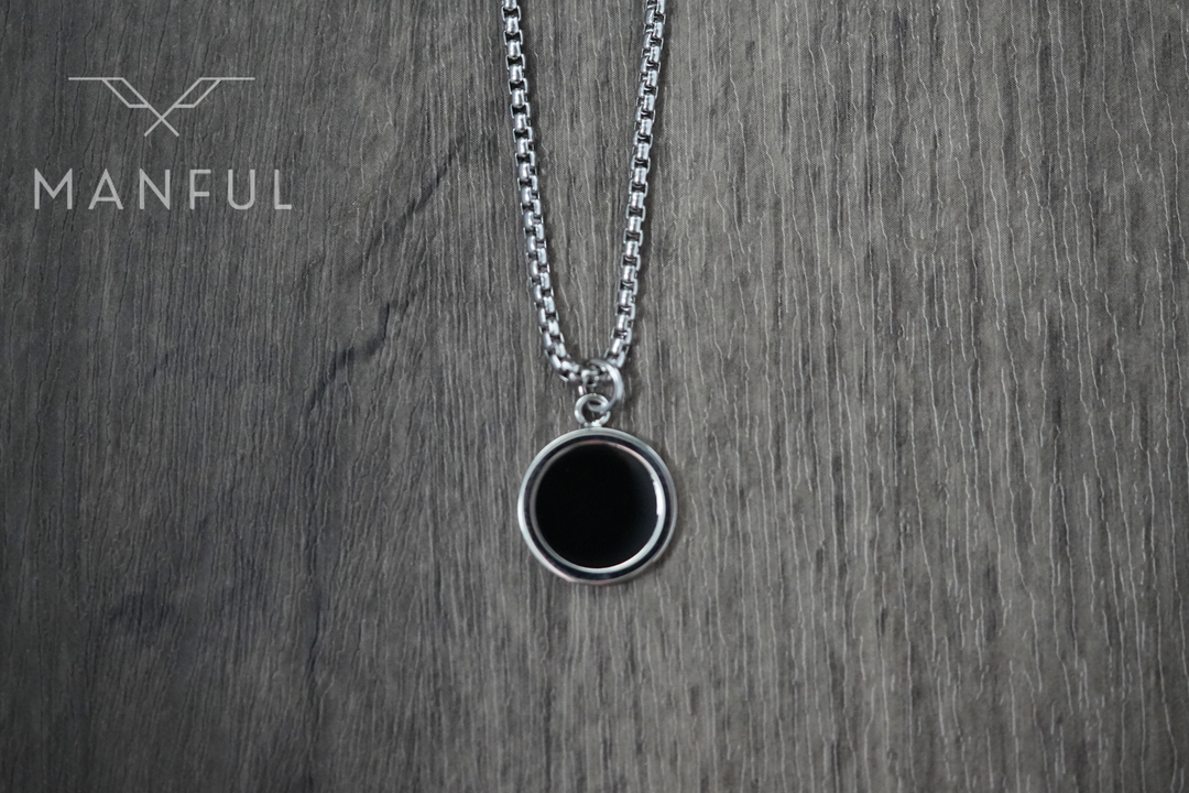 Onyx Circle Necklace, hanging against a wood surface facing the camera