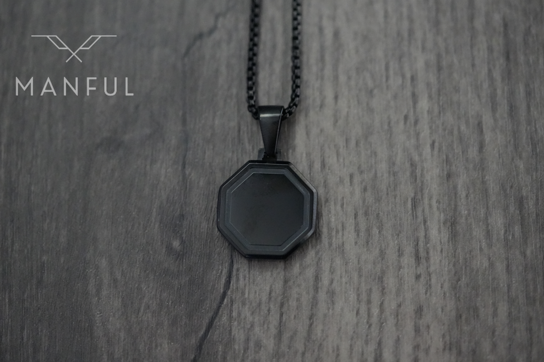 Onyx Octagon Necklace Black, flat lay on light wood with the chain coiled above