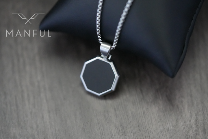 Onyx Octagon Necklace Silver, draped over a black display cushion on a wood surface