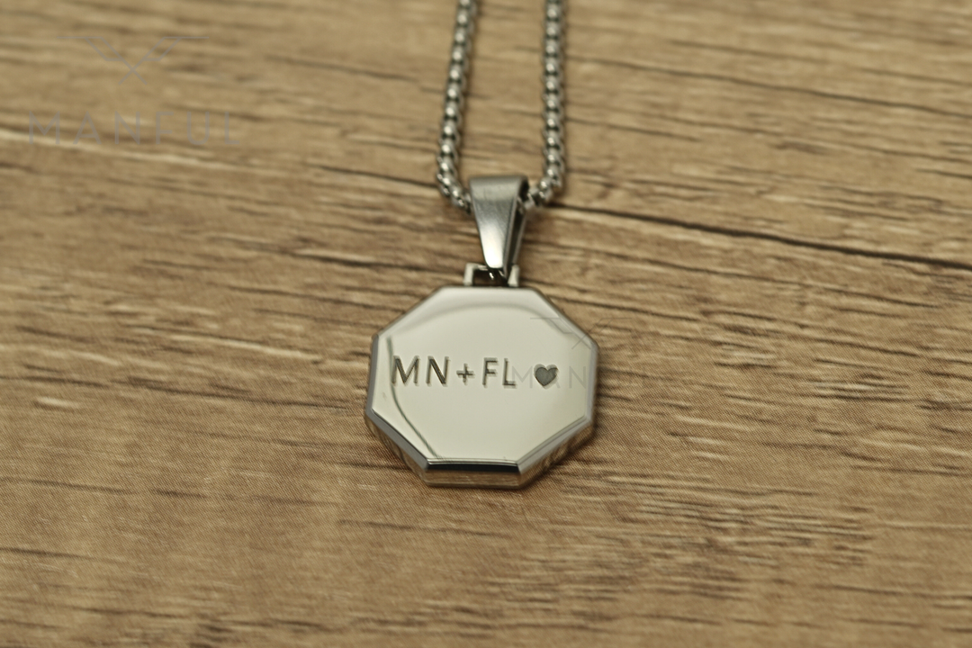 Onyx Octagon Necklace Silver, flat lay on a wood surface showing the engraved reverse
