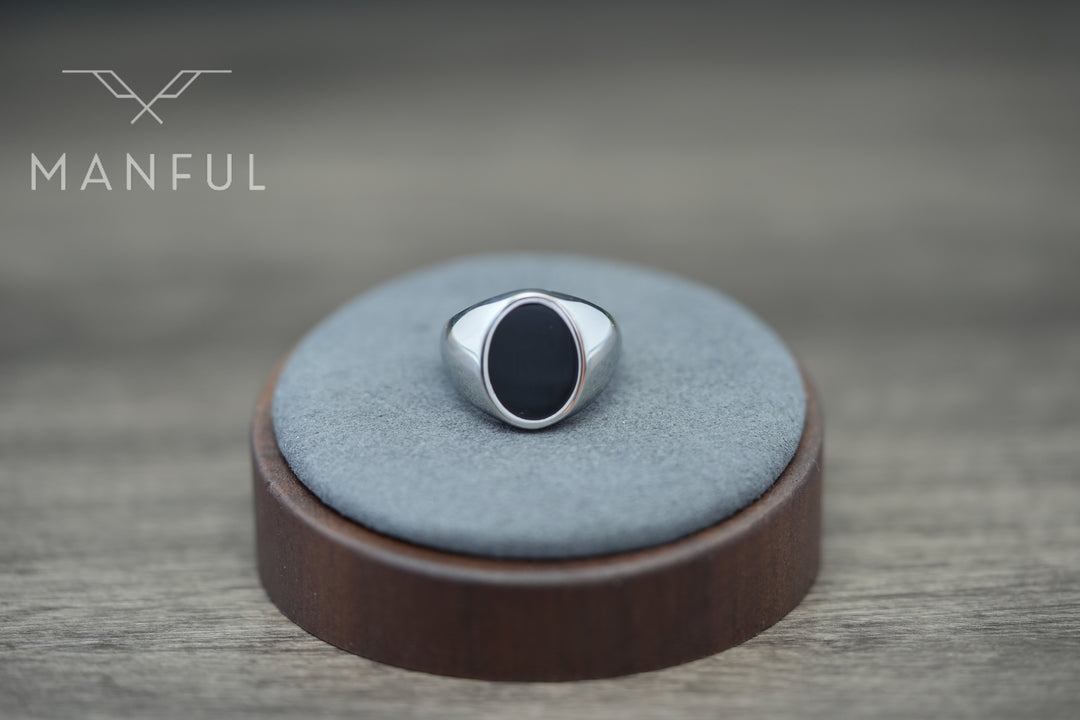 Onyx Oval Signet Ring, displayed on a round grey suede stand with a dark wood base