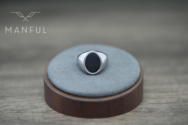 Onyx Oval Signet Ring, displayed on a round grey suede stand with a dark wood base