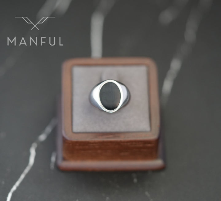 Onyx Oval Signet Ring, displayed on a square grey ring cushion box on dark marble