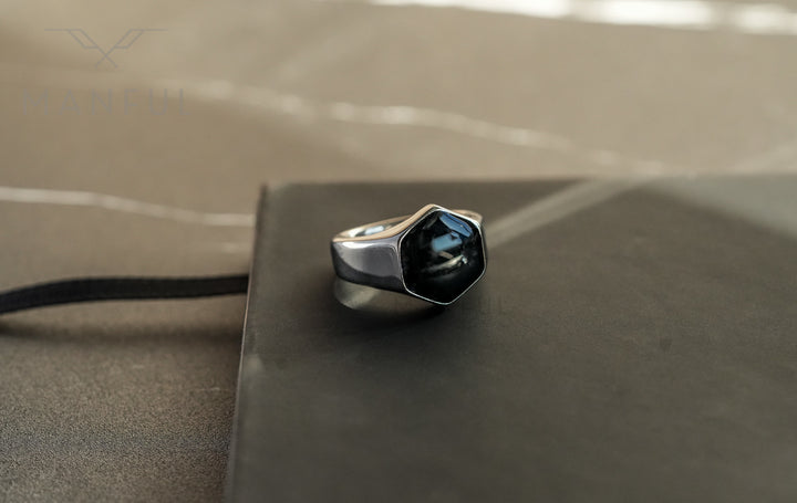 Onyx Silver Hexagon Signet Ring, standing on top of a closed black notebook