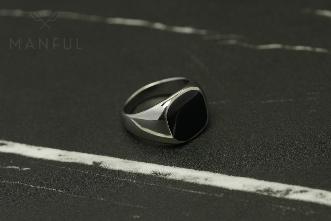 Onyx Signet Ring Silver, angled close up on dark marble with pale veining