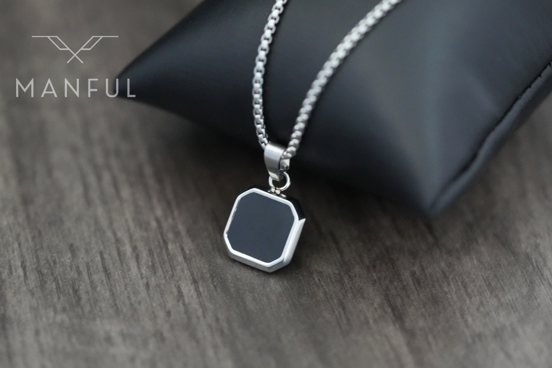 Onyx Square Necklace Silver, pendant draped over a black cushion prop on wood