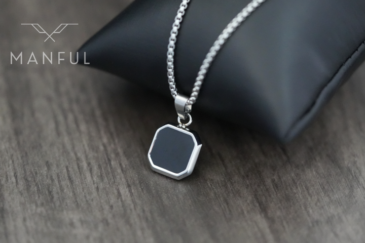 Onyx Square Necklace Silver, pendant draped over a black cushion prop on wood