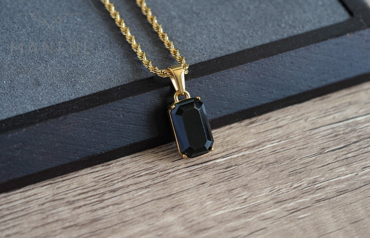 Onyx Stone Pendant Gold, resting on a wood surface beside a dark box corner