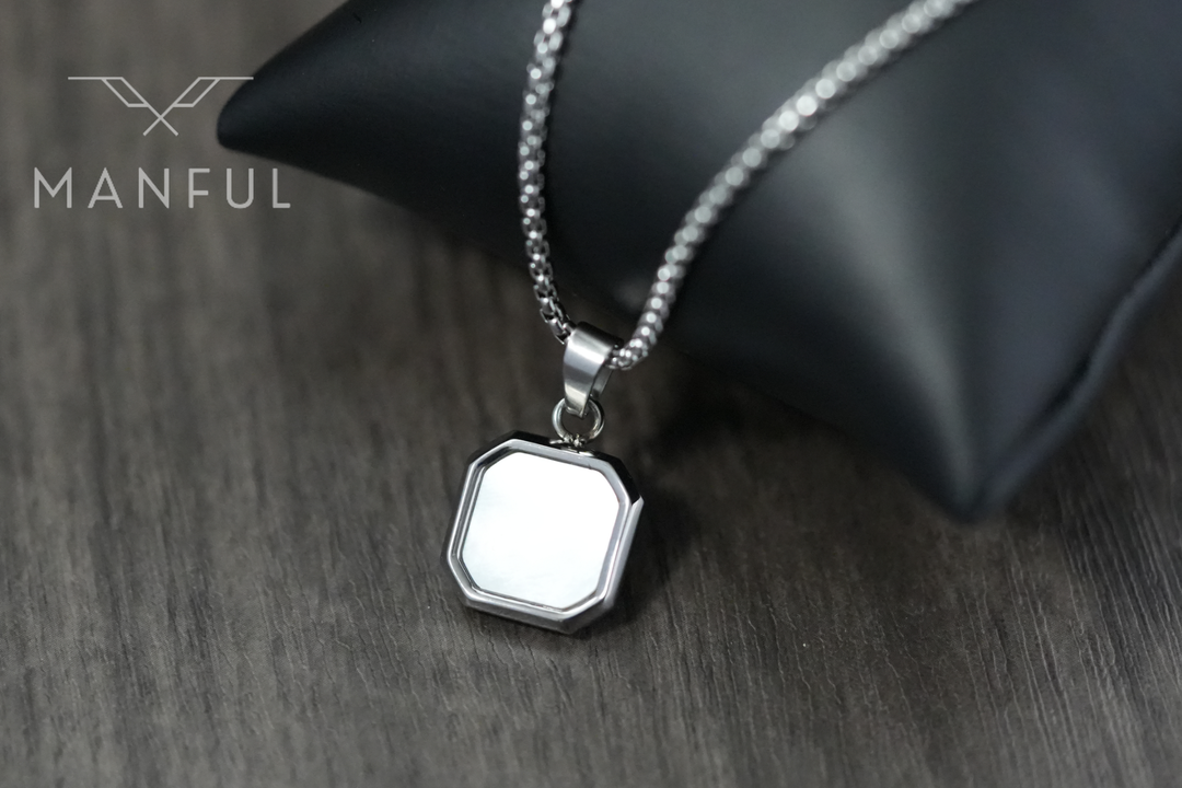 Pearl Square Necklace, pendant leaning against a black leather cushion on a wood table