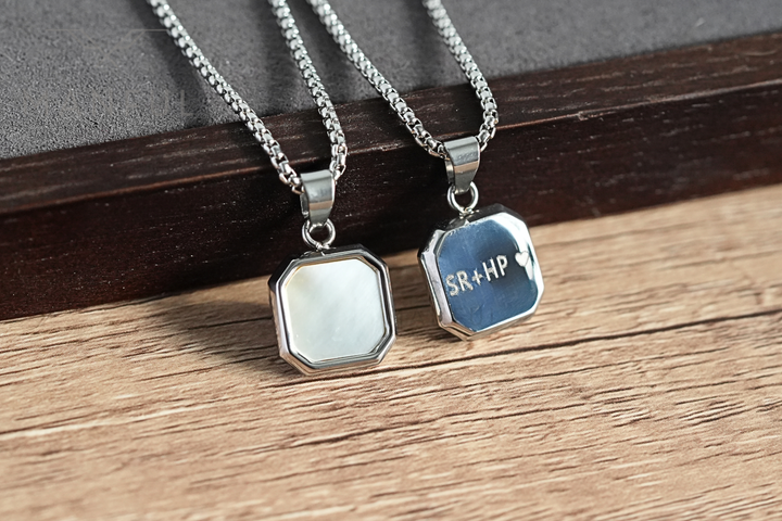 Pearl Square Necklace, paired beside an engraved heart pendant on a wood surface