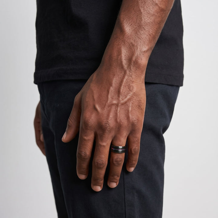 Rainbow Band on a man's finger, his hand hanging at his side