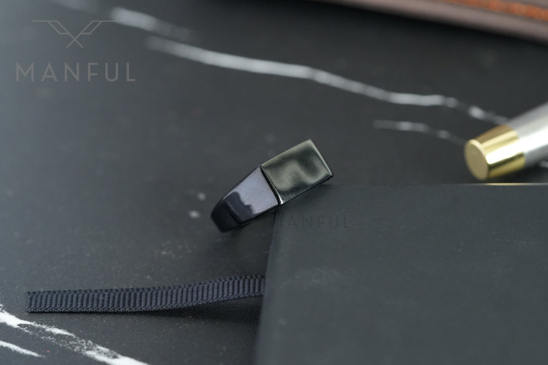Rectangular Signet Ring Black, standing against a notebook edge beside a fountain pen