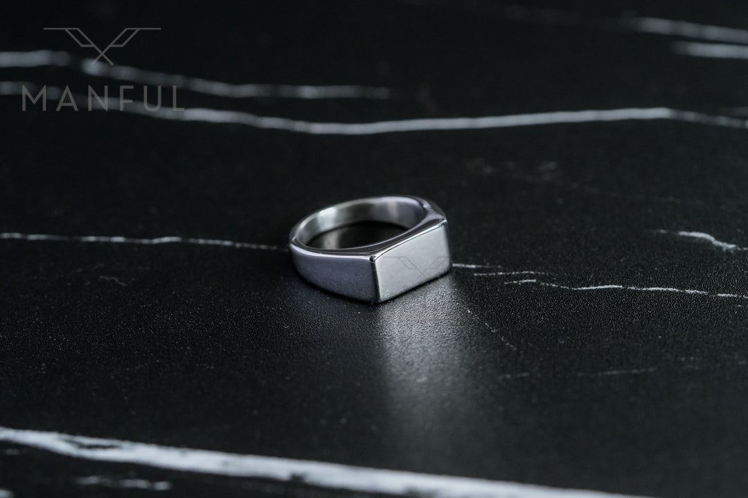 Rectangular Signet Ring Silver, resting on a dark marble surface with white veining