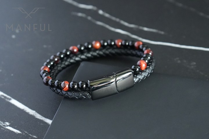 Red Tigers Eye Bead And Leather Bracelet, angled on a dark surface with the clasp facing forward