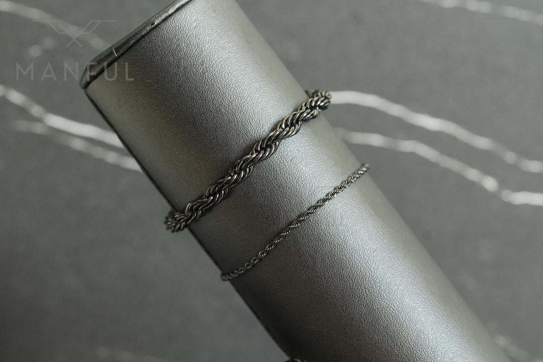 Rope Chain Bracelet Black, draped over a grey leather cylindrical prop in close-up