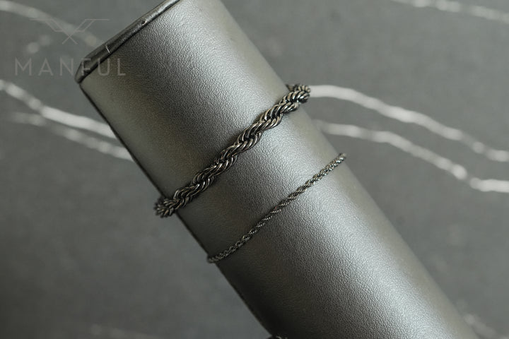 Rope Chain Bracelet Black, draped over a grey leather cylindrical prop in close-up