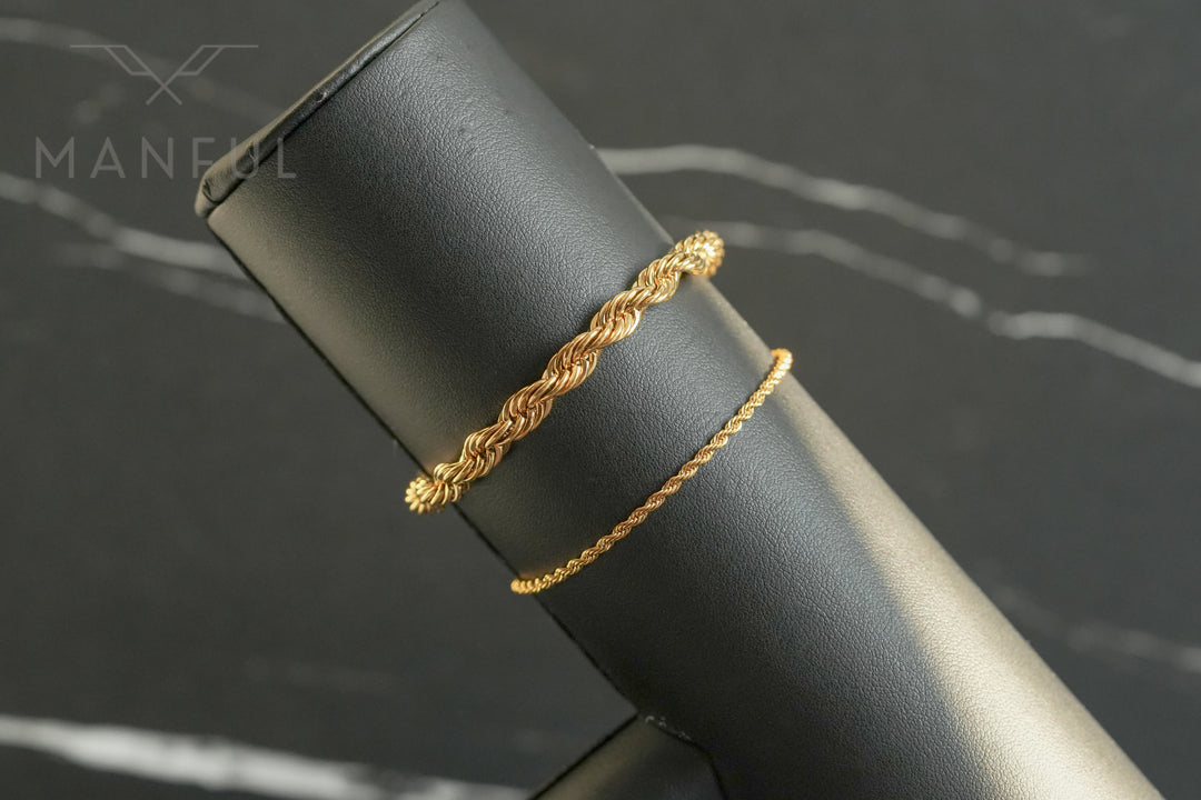 Rope Chain Bracelet Gold, draped over a black stand beside a thinner rope bracelet