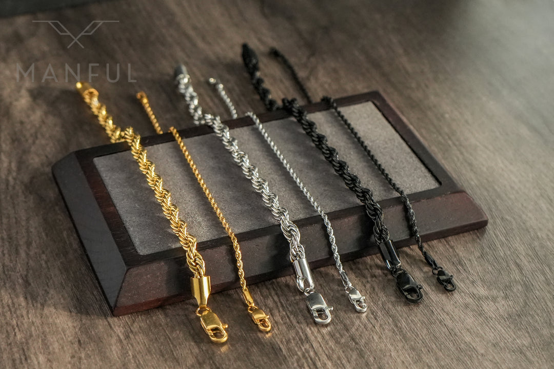 Rope Chain Bracelet Black, draped over a wooden stand alongside gold and silver colourways