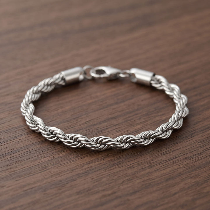 Rope Chain Bracelet (Silver) lying in an open loop on a walnut table