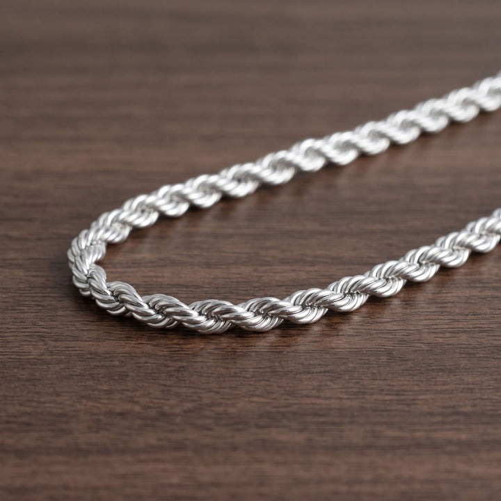 Rope Chain 7mm Silver lying in a loose curve on a walnut table
