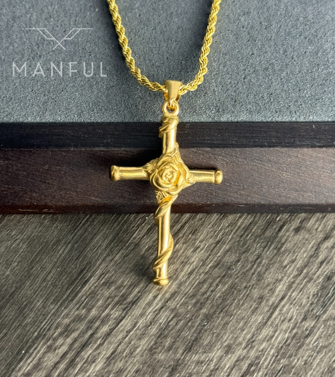 Rose Cross Pendant Necklace Gold, resting flat on a wood and stone surface at an angle