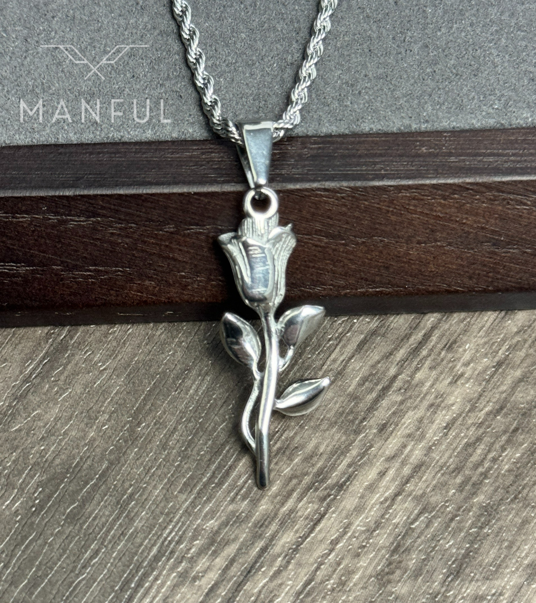 Rose Pendant Necklace Silver, propped against a stone and dark wood ledge, chain draped down