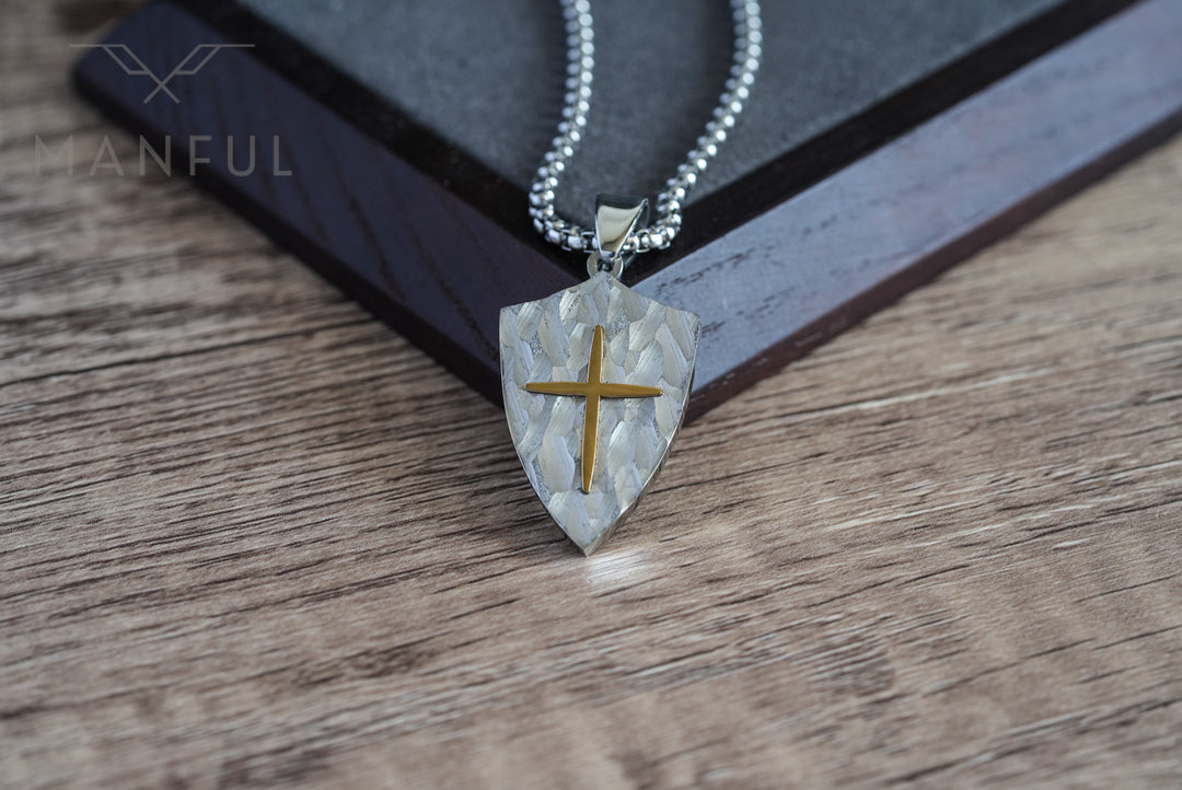 Shield Cross Pendant Silver, propped against a wooden block corner with the chain draped over it