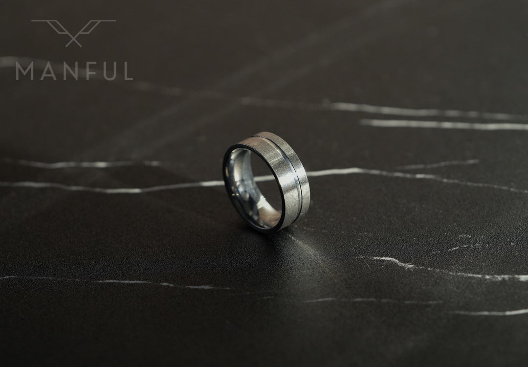 Off-balance Silver Band, standing on a black marble surface with white veining