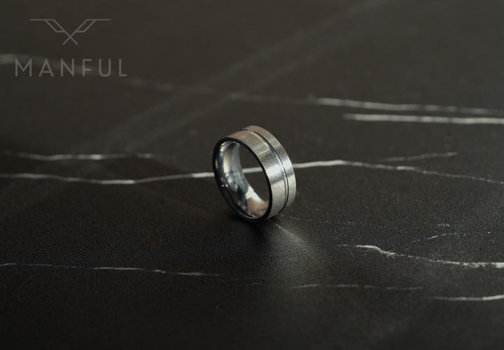 Off-balance Silver Band, standing on a black marble surface with white veining