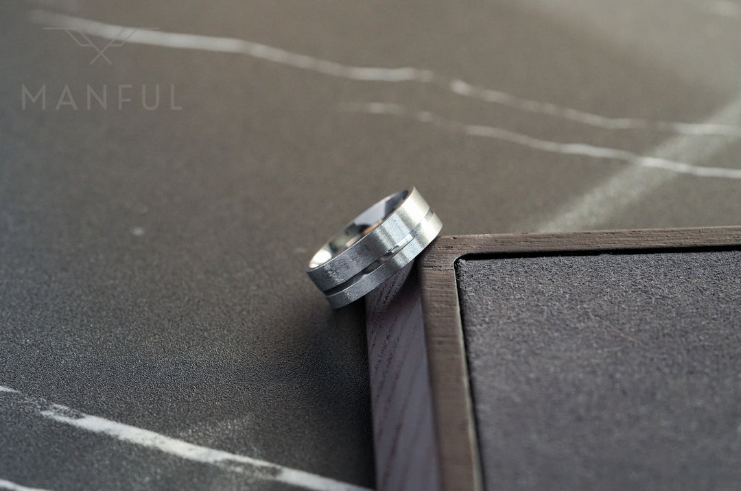 Off-balance Silver Band, propped against a wooden frame corner on a marble surface