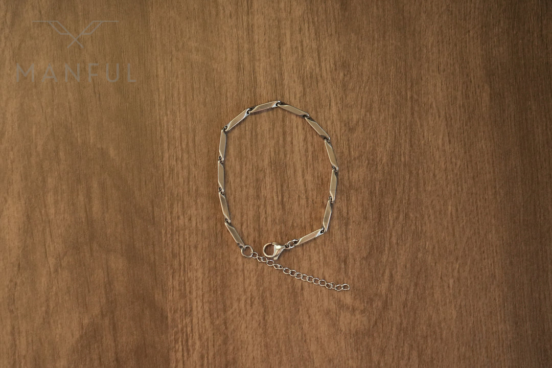 Block Chain Bracelet Silver, laid in a circle on a wood surface showing the clasp and extension chain
