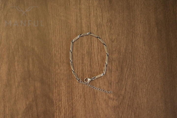 Block Chain Bracelet Silver, laid in a circle on a wood surface showing the clasp and extension chain