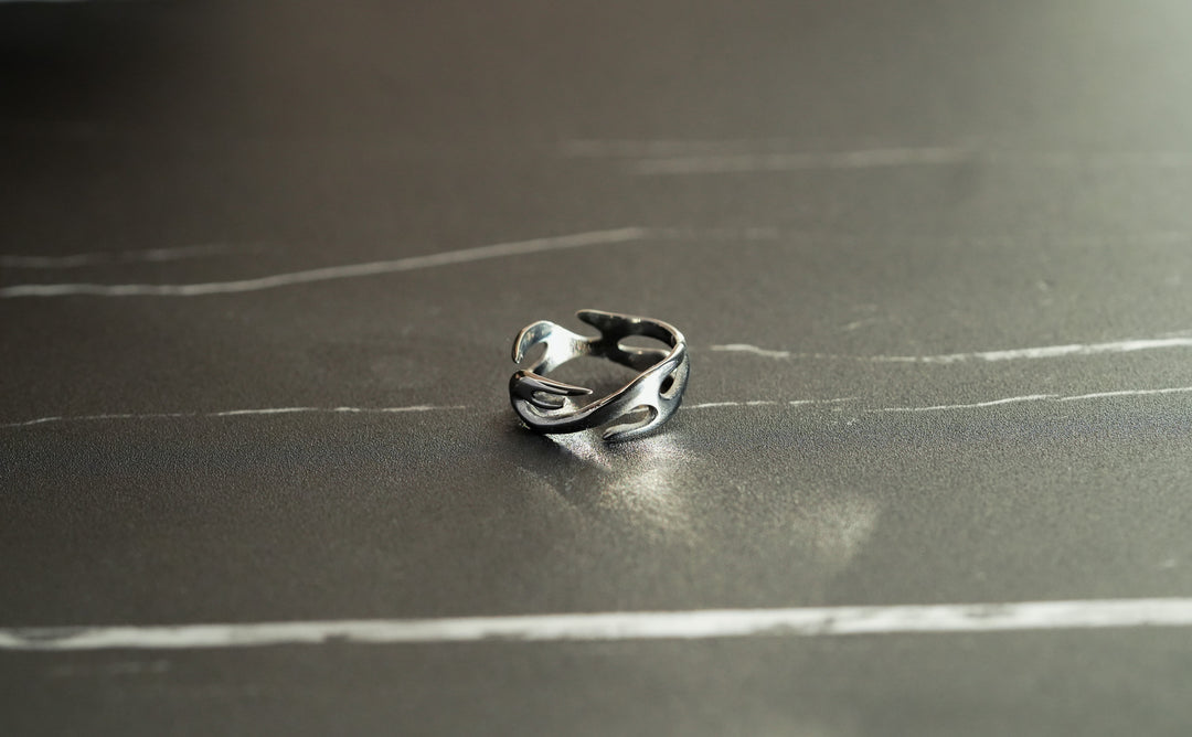 Silver Flame Ring, on a dark surface, shot from above at an angle