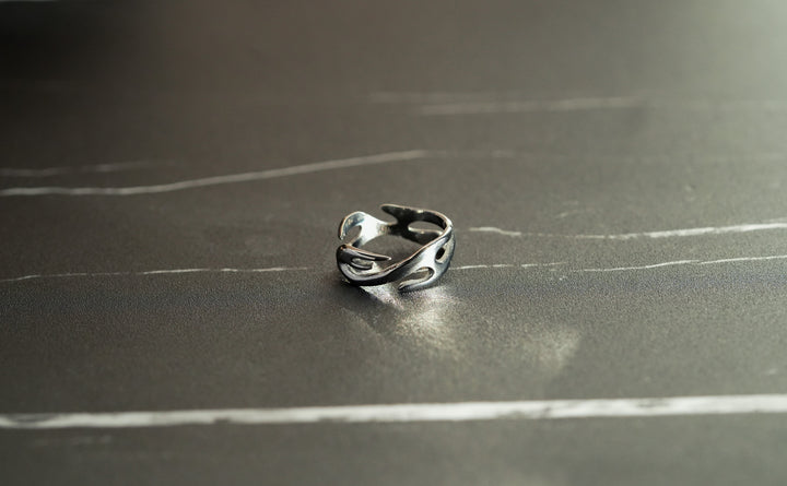 Silver Flame Ring, on a dark surface, shot from above at an angle