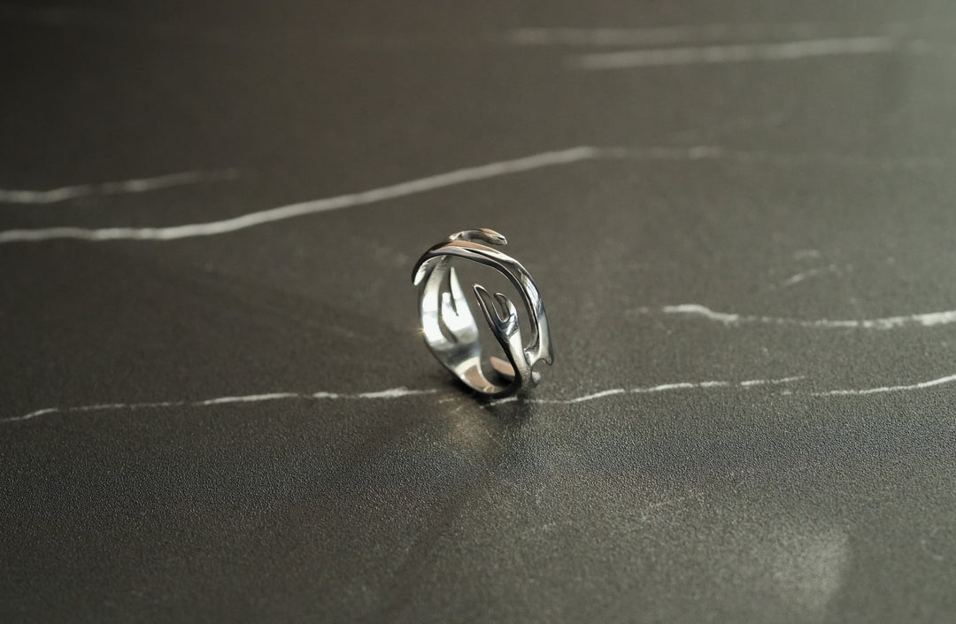 Silver Flame Ring, on a dark surface, tilted to show the swirling band