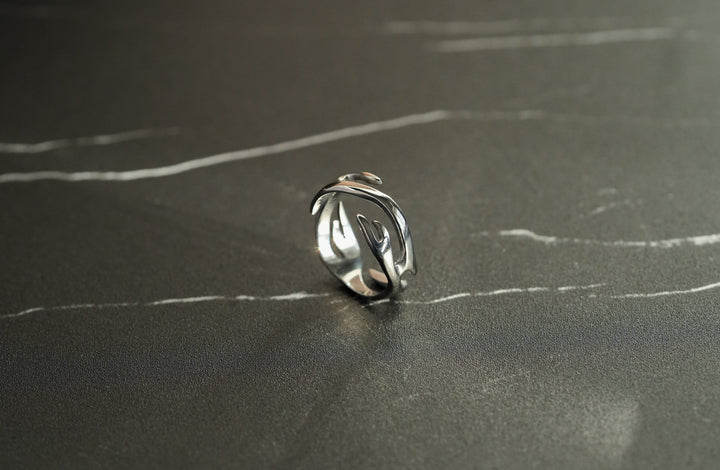 Silver Flame Ring, on a dark surface, tilted to show the swirling band