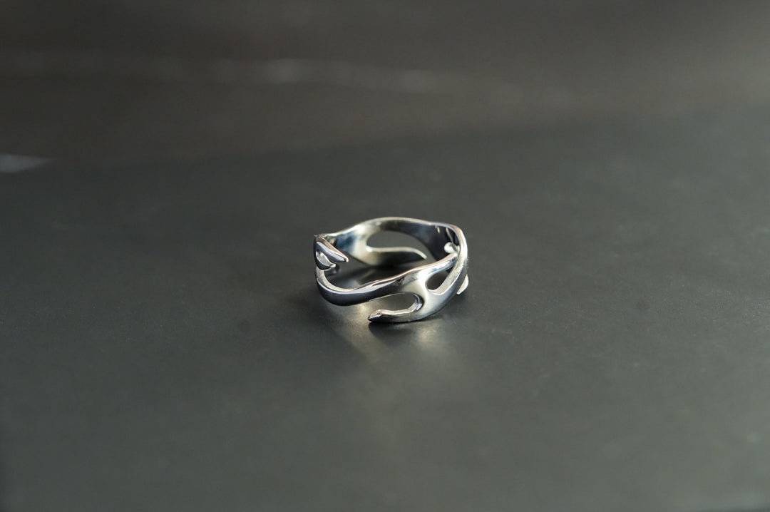 Silver Flame Ring, close side view resting on a dark surface